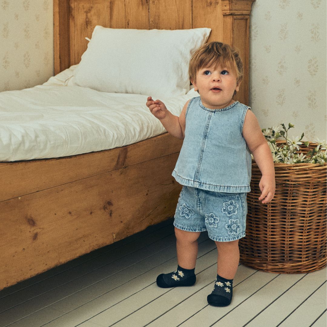 デニムの服を着た子どもがベッド脇に立つ着用シーン