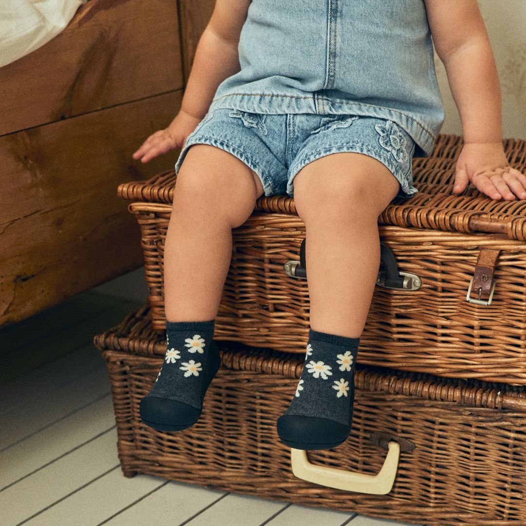 籐のトランクに座る子どもの足元アップ