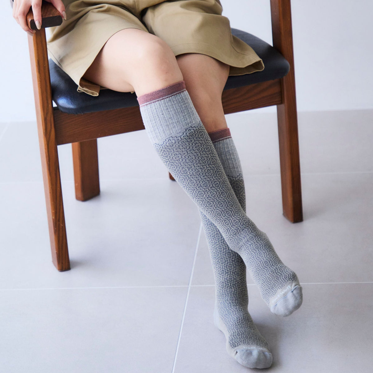 モザイク柄のニーハイソックスを履き椅子に座る脚元