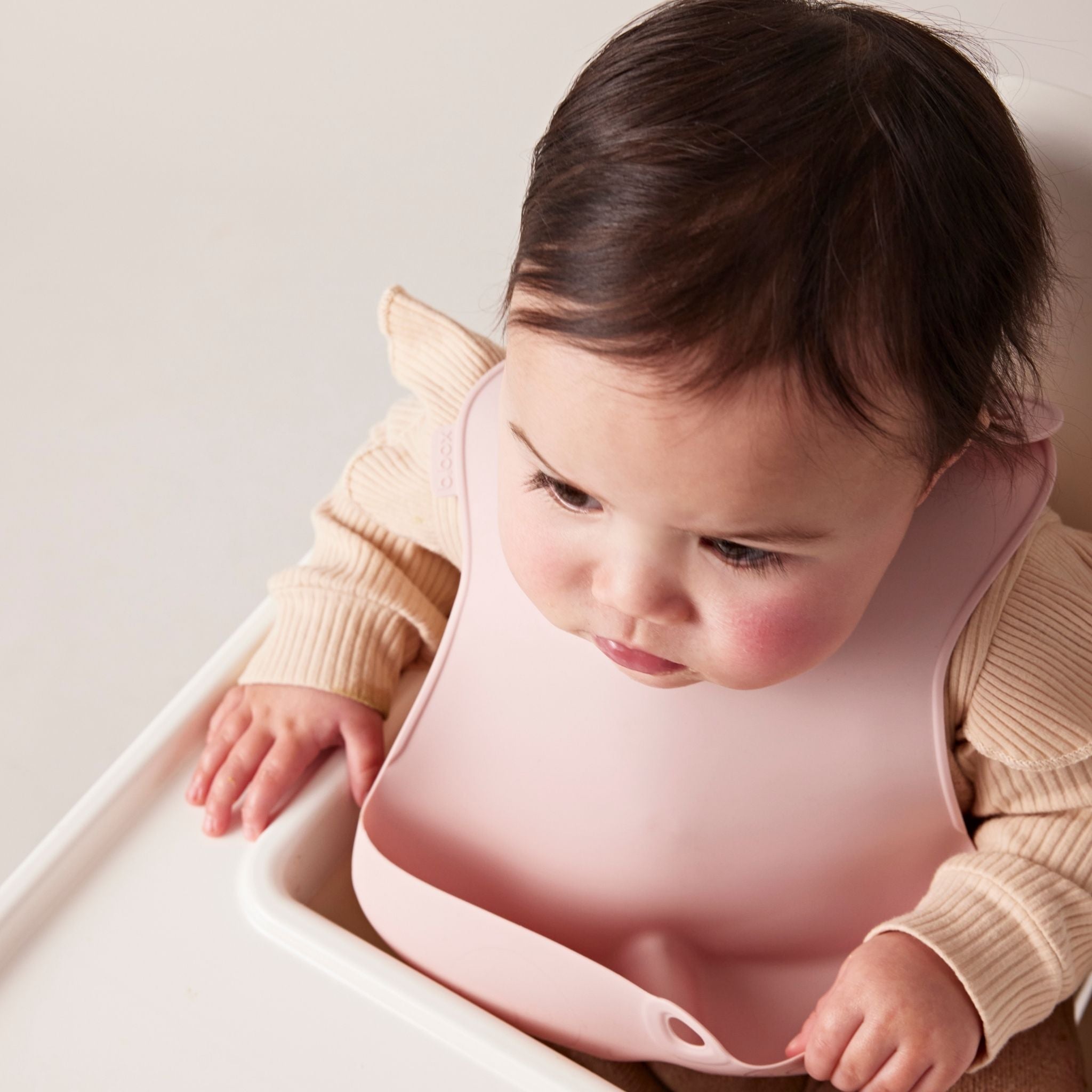 ビーボックスのピンクカラーのシリコンビブを身につけている女の子の赤ちゃん