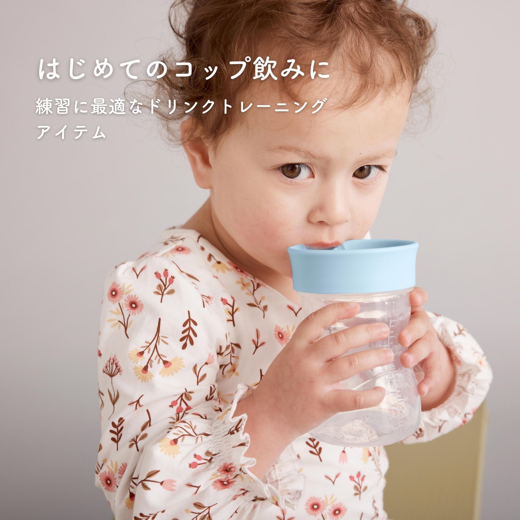 はじめてのコップ飲みに ブルーの蓋の付いたコップ飲み練習アイテムを飲んでいる赤ちゃん